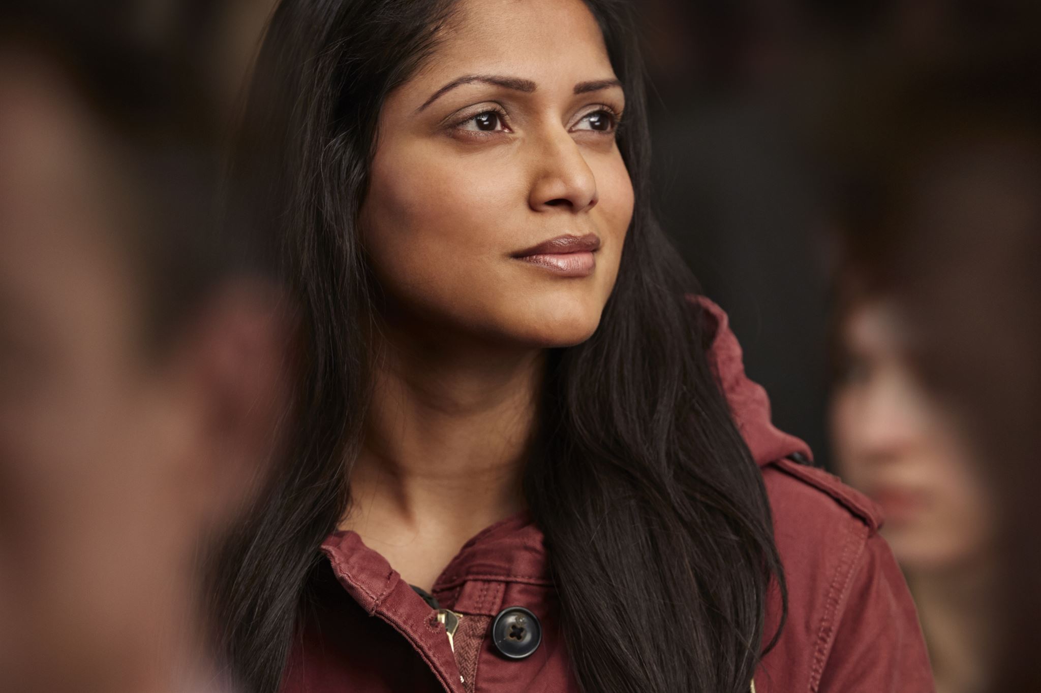Portrait-of-young-women-in-burgundy-jacket-surrounded-by-others-looking-away